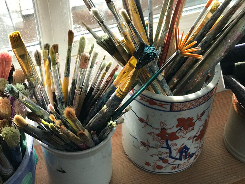 Close up of paintbrushes in pots